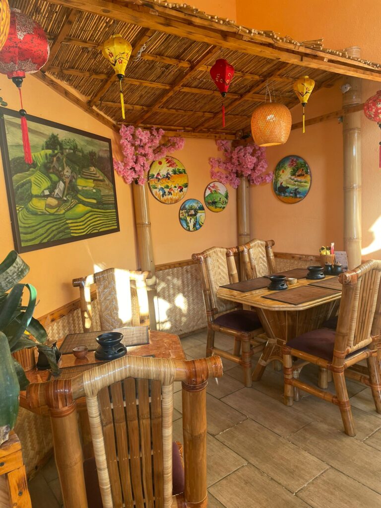 Ein gemütliches, asiatisch dekoriertes Restaurant mit Bambusmöbeln und farbenfrohen Laternen.