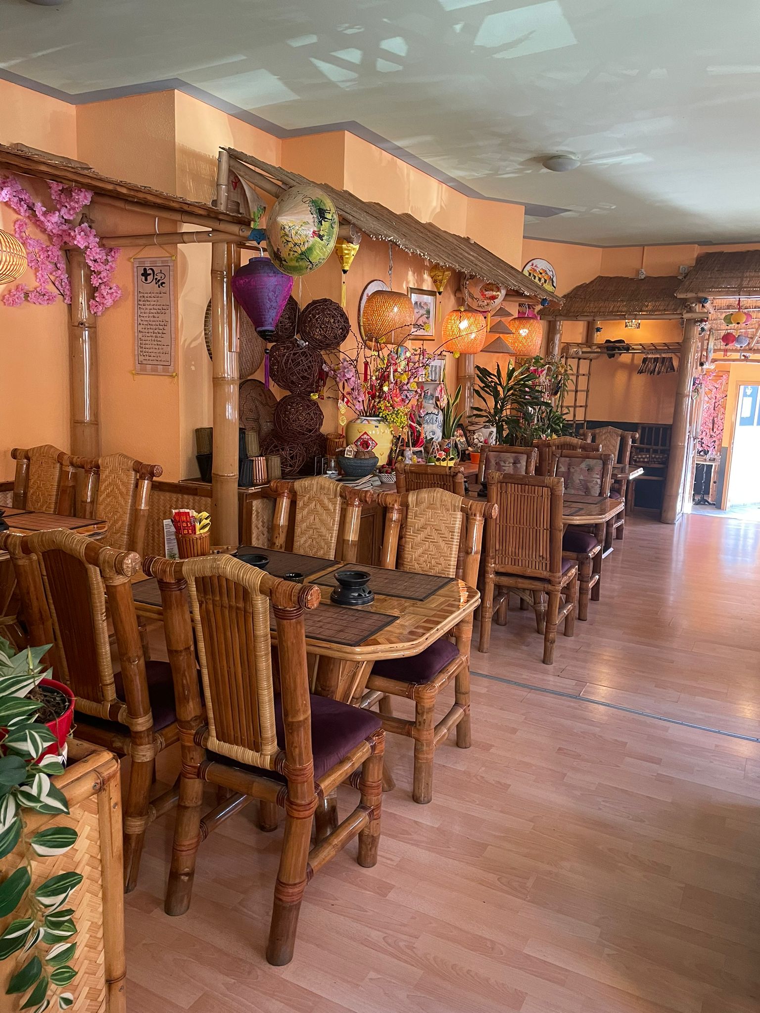 Ein leerer, einladender asiatischer Restaurantbereich mit Bambusmöbeln und bunten Laternen.